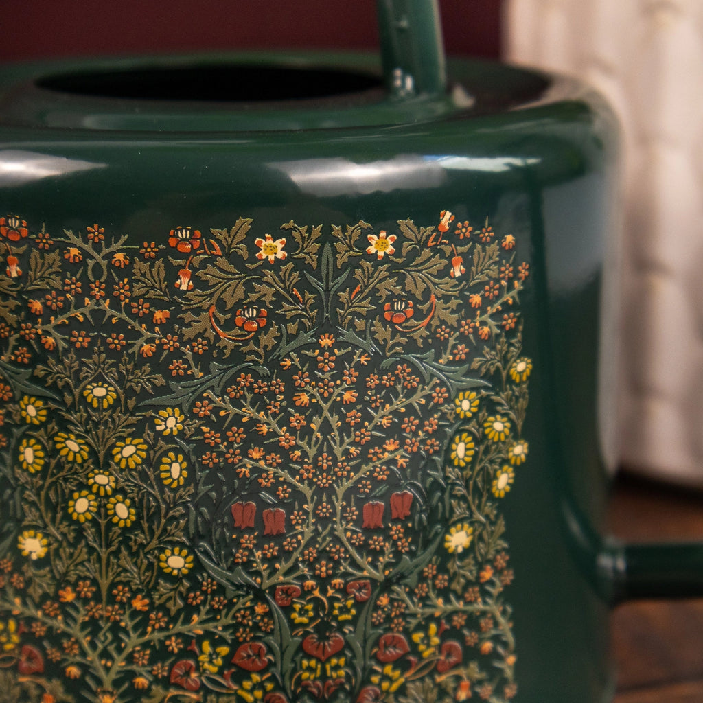Green watering can close up with floral pattern on a blurred background