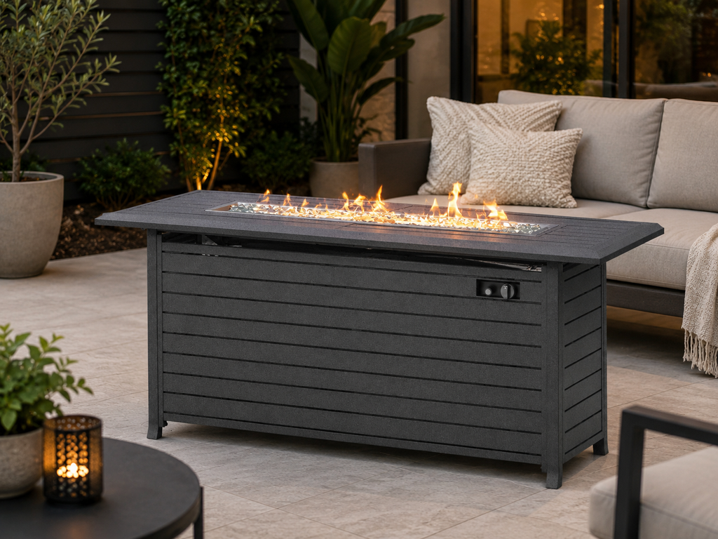 A dark gray outdoor fire pit storage table with a built-in firebox and visible flames, placed on a patio next to a light gray sofa with pillows. Leading Landscapes Canterbury