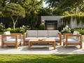 Outdoor patio set with wooden furniture and white cushions in a garden setting. -Leading Landscapes Canterbury