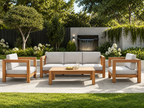 Outdoor patio set with wooden furniture and white cushions in a garden setting. -Leading Landscapes Canterbury