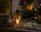 Wooden lantern with a lit candle on a wooden surface in a garden setting - Leading Landscapes Canterbury