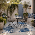 Outdoor patio with a small table and chairs on a blue patterned rug - Leading Landscapes Canterbury