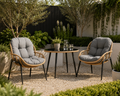Two wicker chairs with gray cushions and a small round table in a garden - Leading Landscapes Canterbury.