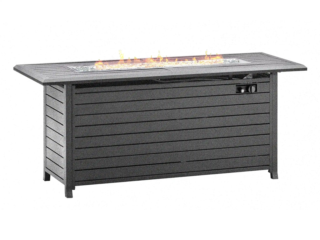 A rectangular outdoor fire pit table with a dark gray slatted body, featuring a glass wind guard and visible orange flames burning in the firebox on top, isolated on a white background. Leading Landscapes Canterbury