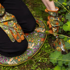 Person wearing floral gardening gloves and a matching kneeling pad in a garden setting.