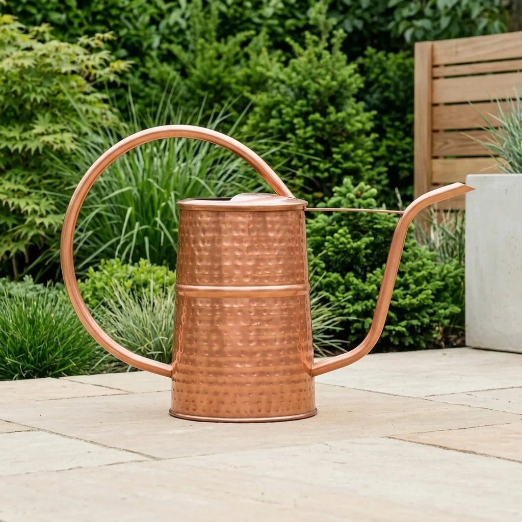 Copper watering can on a patio with greenery in the background - Leading Landscapes Limited